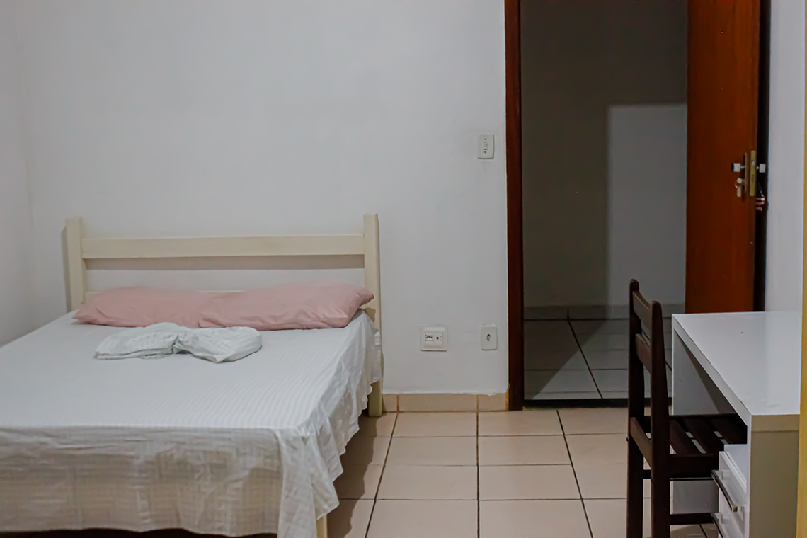 uma cama de casal e uma porta aberto, e também uma mesa de escritorio simples