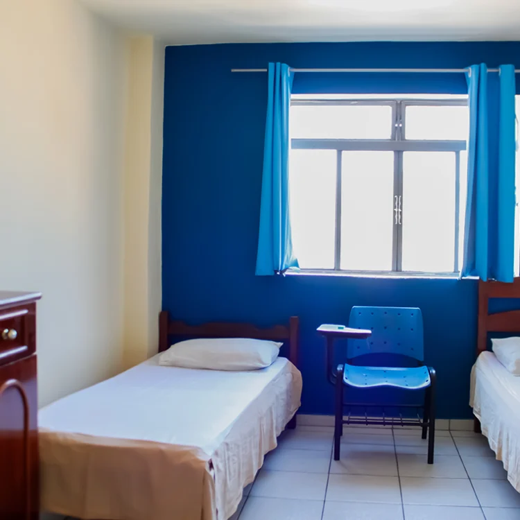 foto de um quarto com duas camas de solteiro, uma janela e uma cadeira