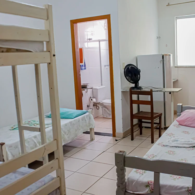 imagem de entrada de um quarto onde se ve uma beliche na sua esquerda e duas camas de solteiro normais