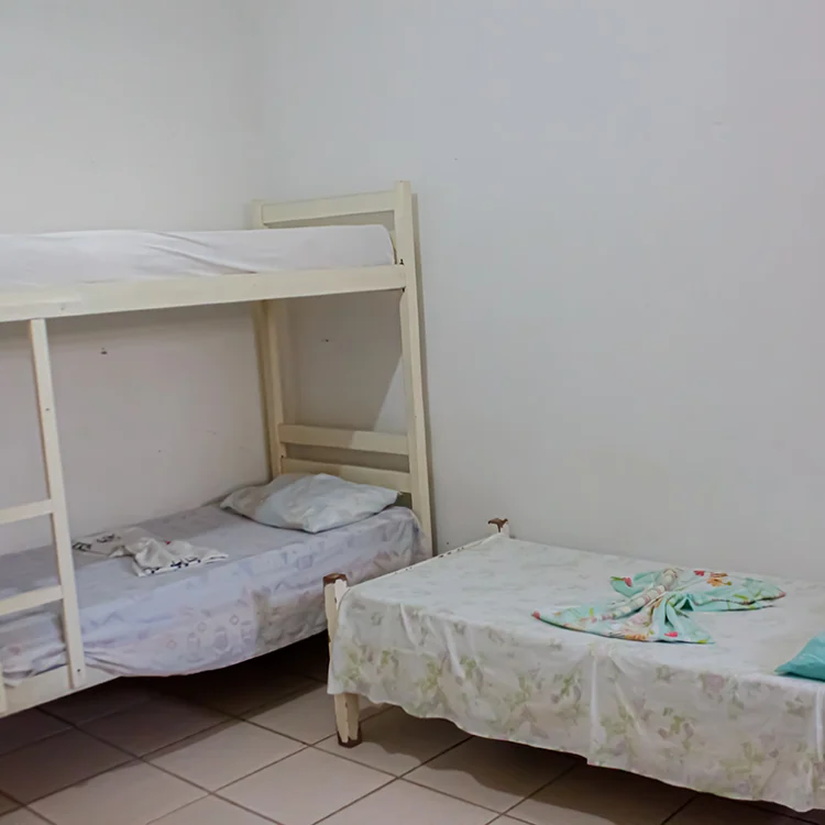 a imagem de um quarto com paredes brancas, uma cama de solteiro branca e um beliche branco