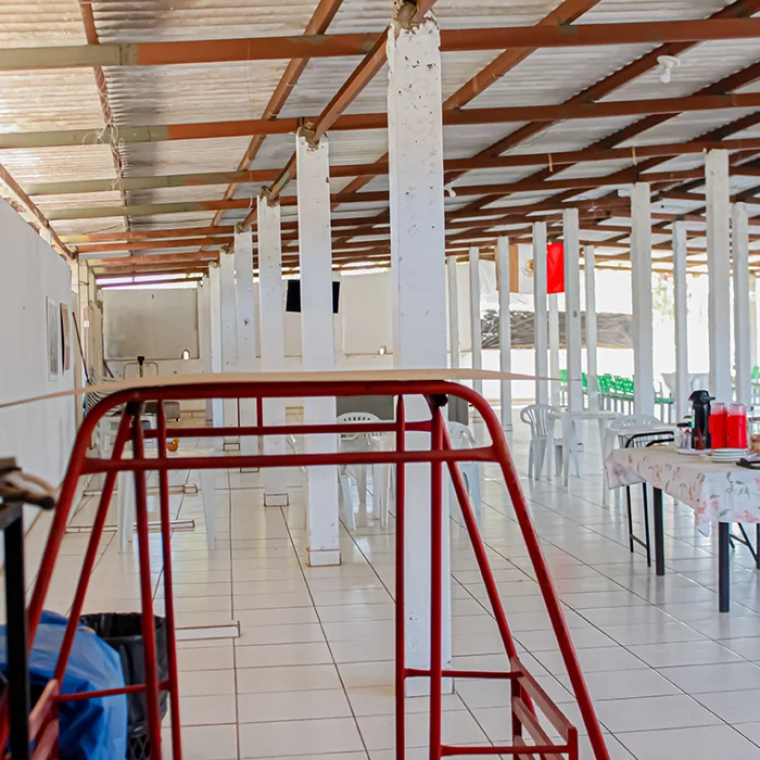 Na imagem se ve um patio com várias mesas e cadeiras, onde é a área de convivência das suites caicara